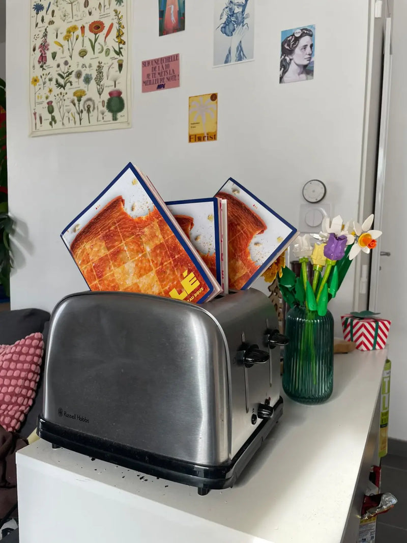 Deux cahiers de mots fléchés GRILLÉ qui sortent d'un toaster comme des tartines grillées