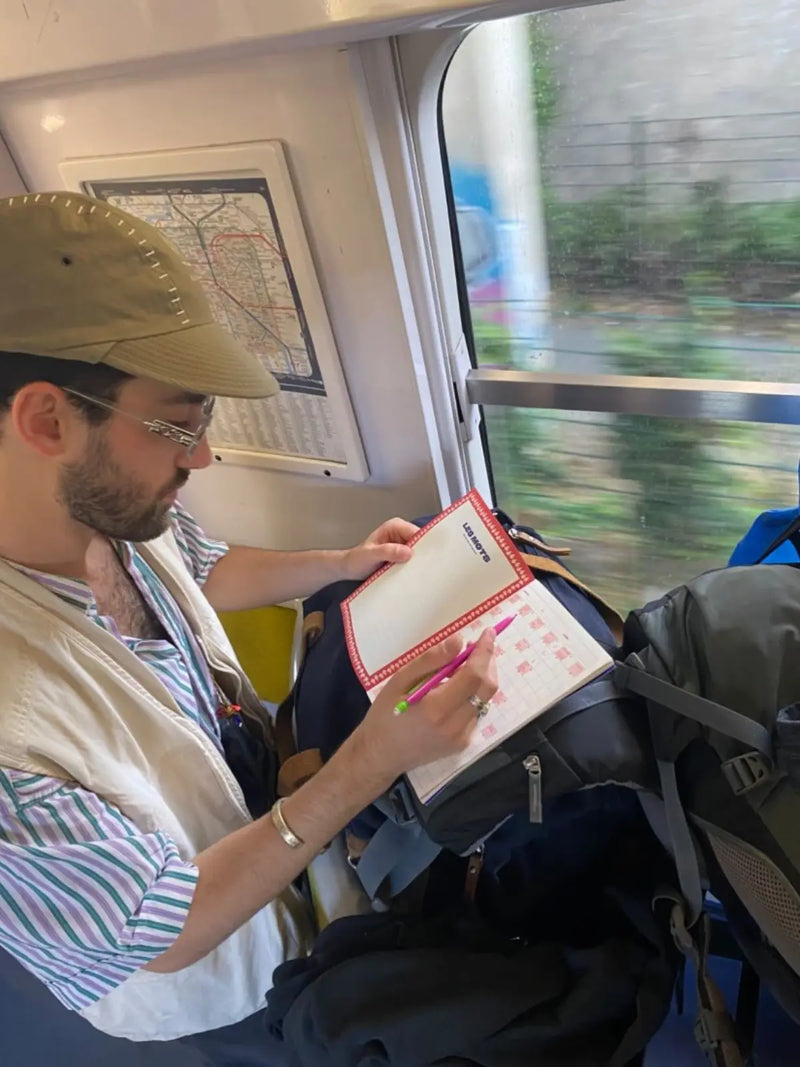 Voyageur remplissant un cahier de mots fléchés GRILLÉ dans le train avec sac à dos