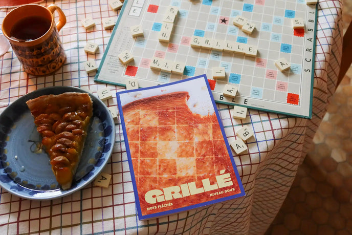 Cahier Grillé niveau doux ouvert sur plateau avec café, pizza et mots fléchés modernes