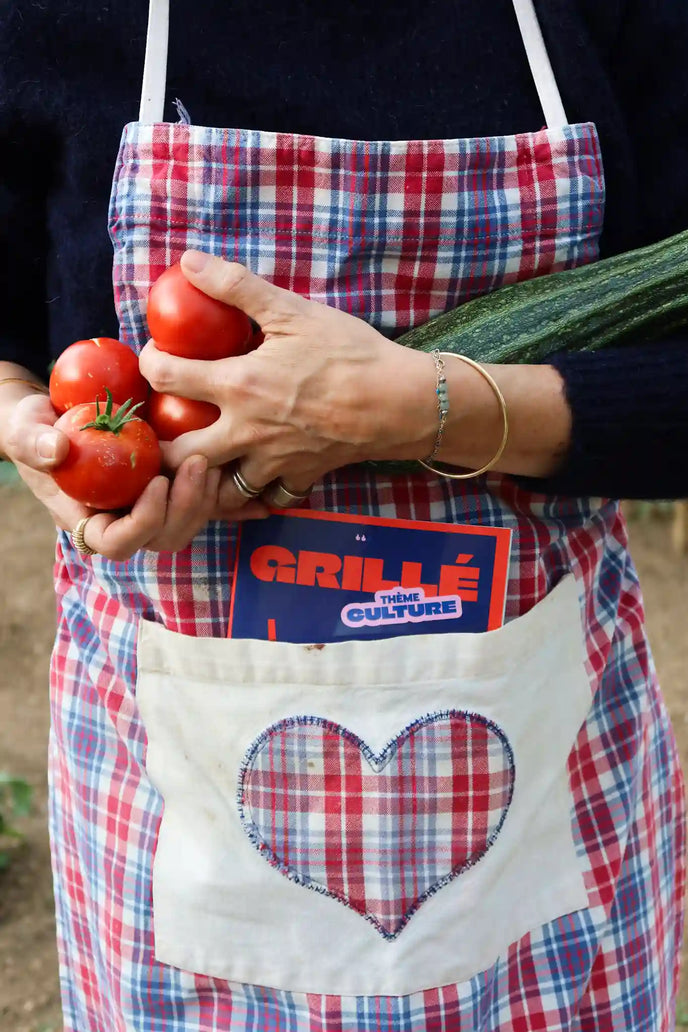 Femme tenant des tomates fraîches avec un cahier Grillé thème culture dans son sac à carreaux rouge