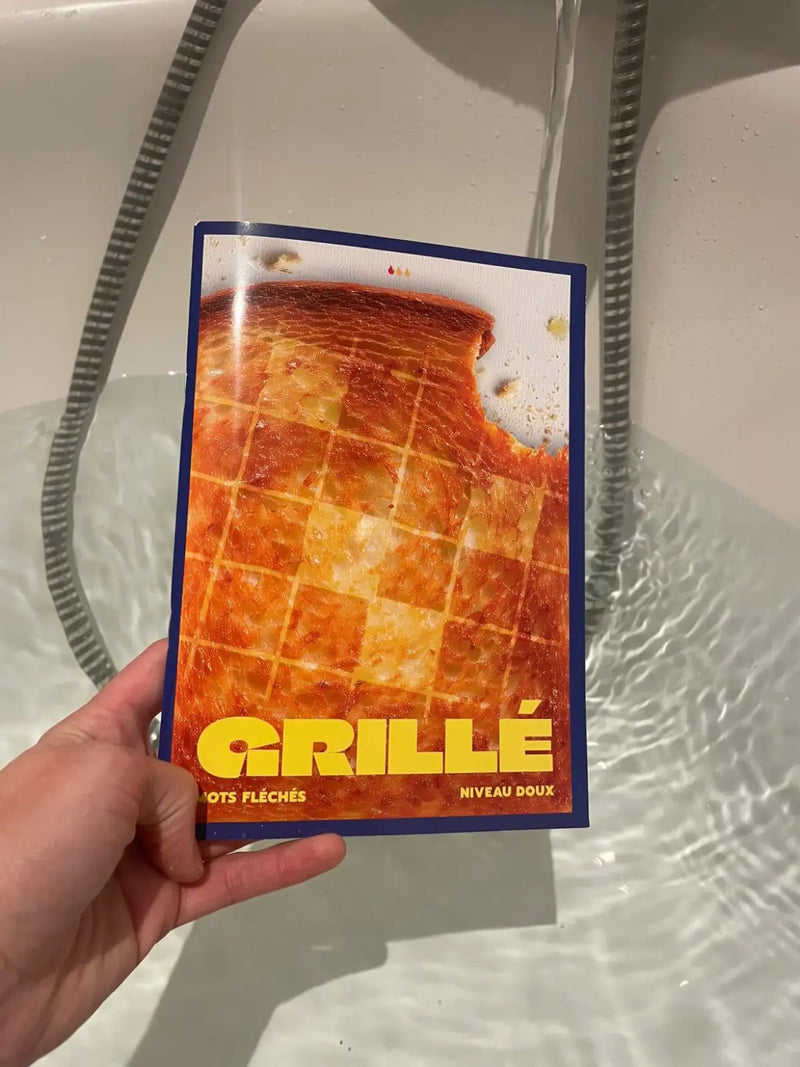 Main tenant un cahier de mots fléchés GRILLÉ niveau Doux dans un bain