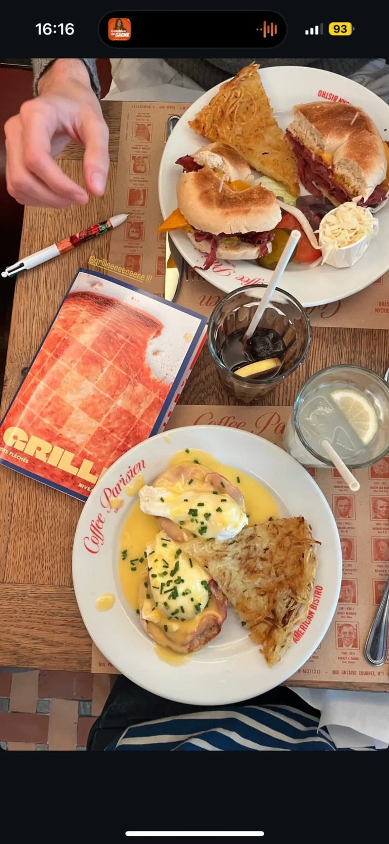Cahier de mots fléchés GRILLÉ niveau Doux sur table de brunch parisien avec œufs bénédictine et sandwich